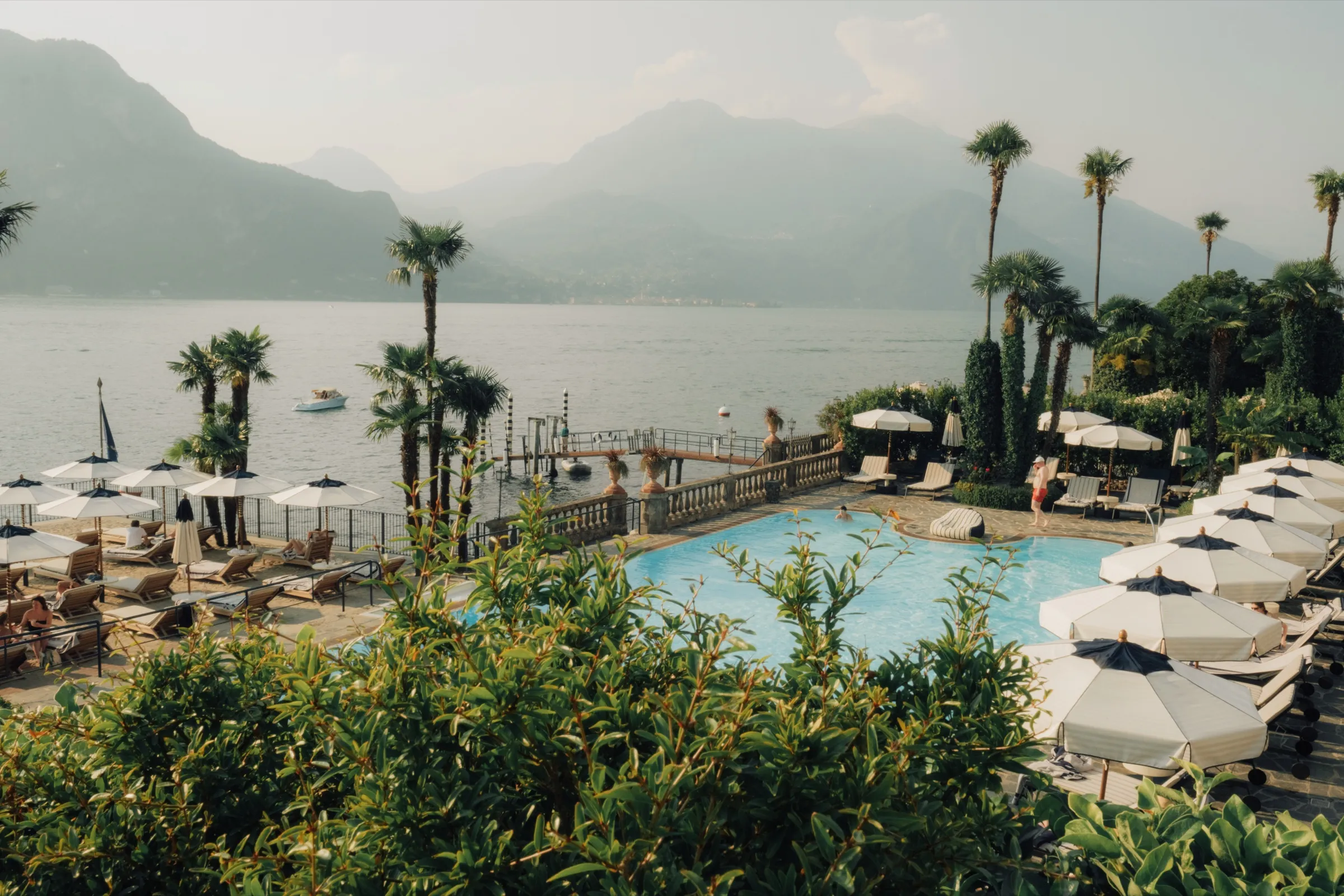 Hotelzwembad met palmen en parasols aan het Comomeer